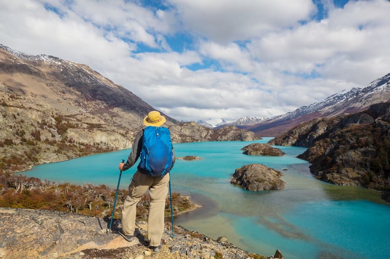 A hiker looking down on a turquoise lake among rocky hills