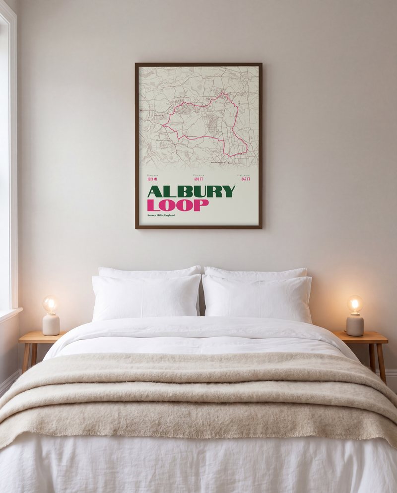 A Albury Loop walking print in Cream, in a dark wood frame, above a bed